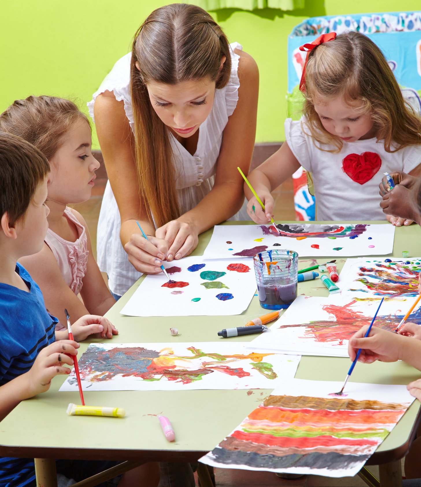 Nursery Teacher Painting with Children in Kindergarten
